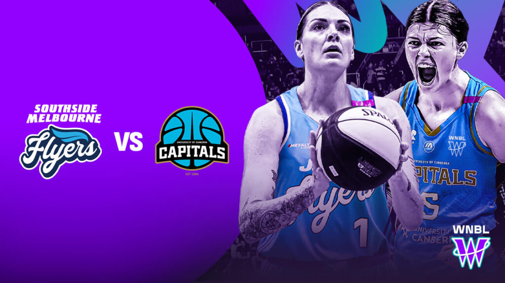 Two women in purple and blue jerseys playing basketball on an outdoor court.