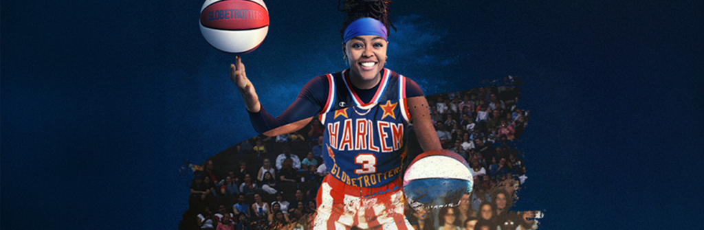 A female Harlem Globetrotter in a basketball uniform stands confidently, holding a basketball in her right hand.