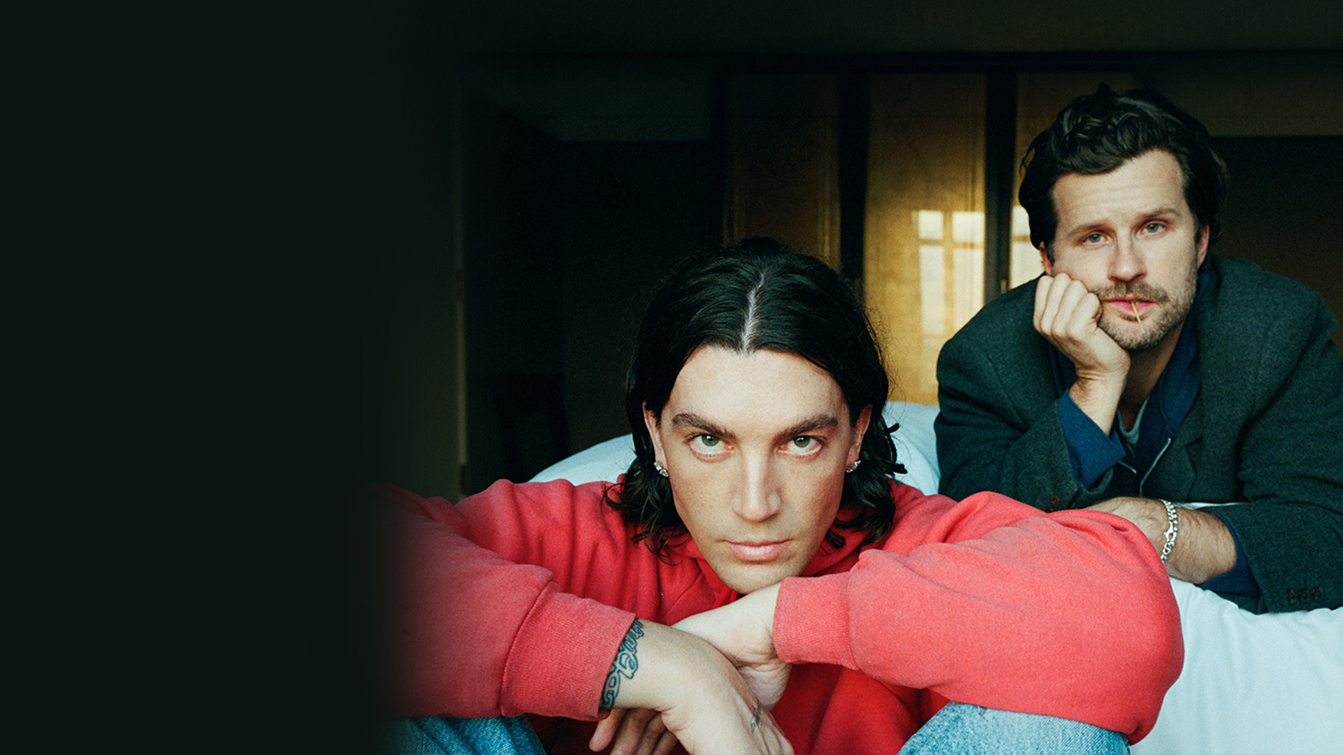 LANY band members sitting on a bed with serious poses.
