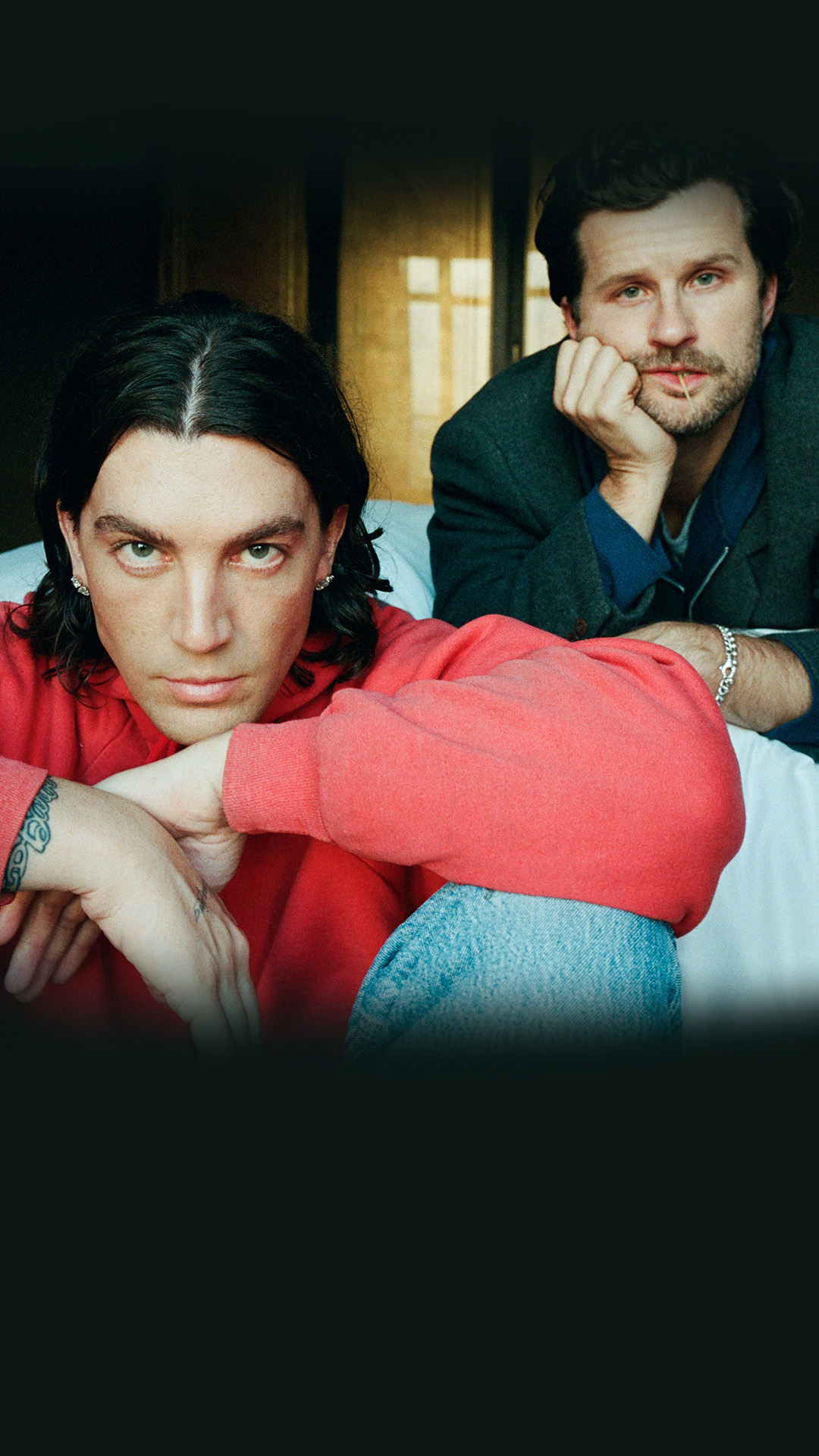 LANY band members sitting on a bed with serious poses.