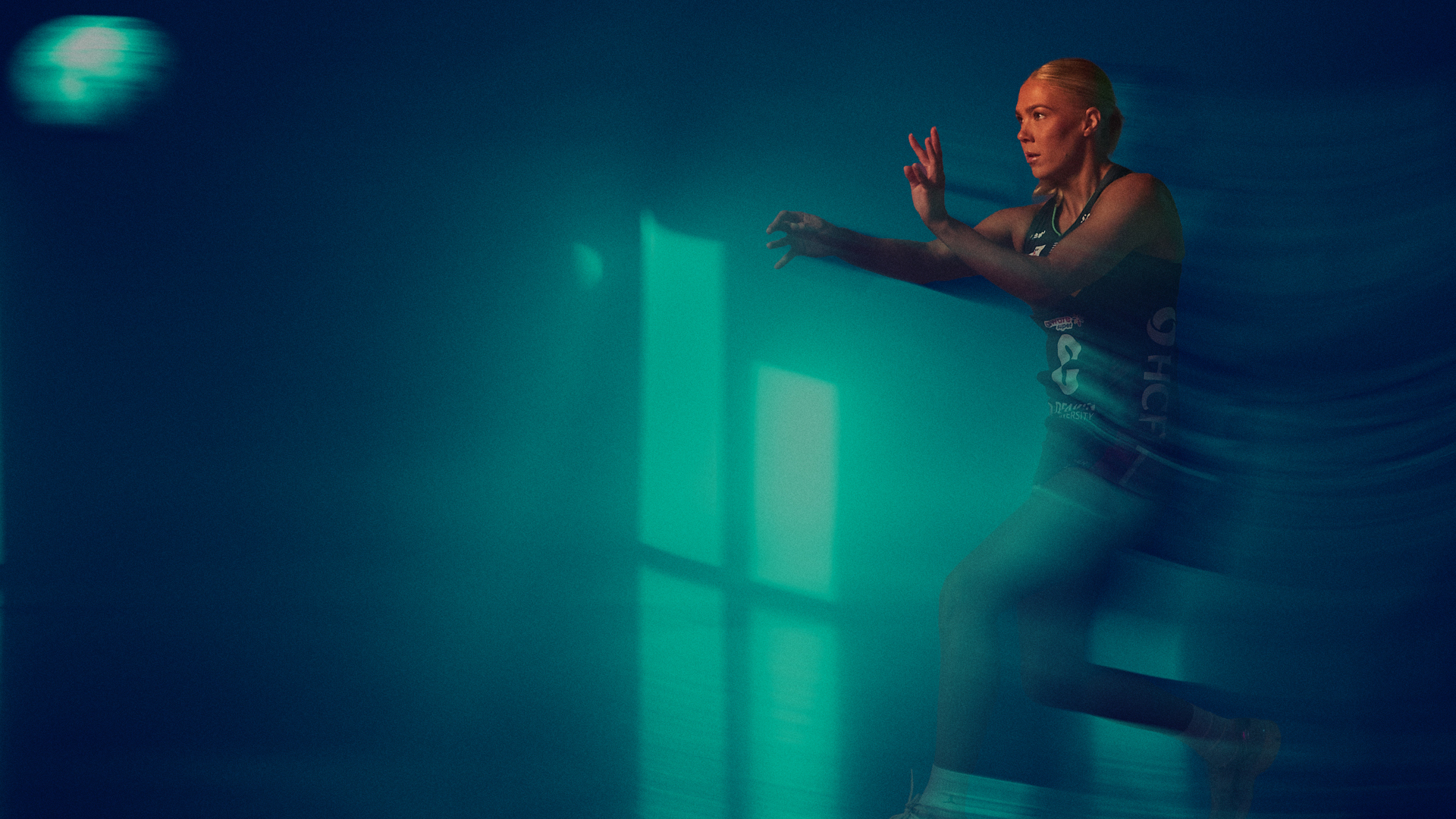 Melbourne Vixens netballer strikes an action pose against a green and blue background.