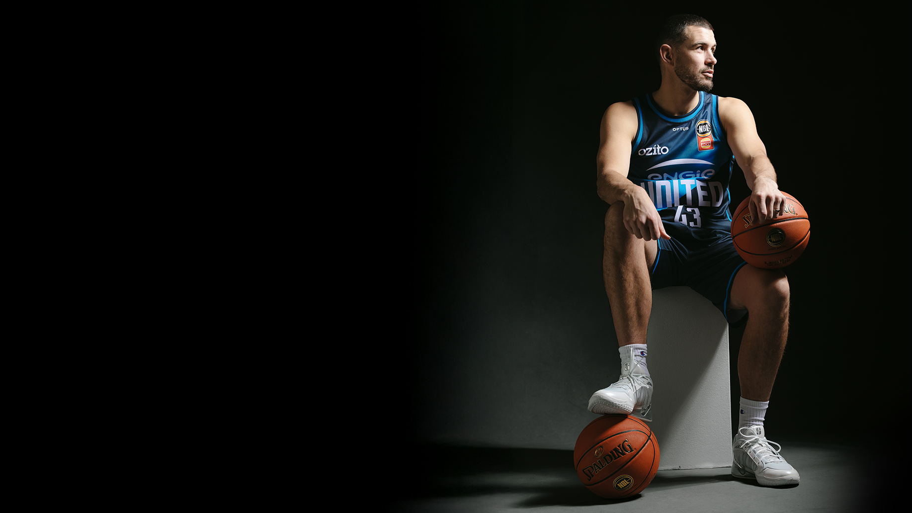 Melbourne United basketball sitting and posing with two basketball.