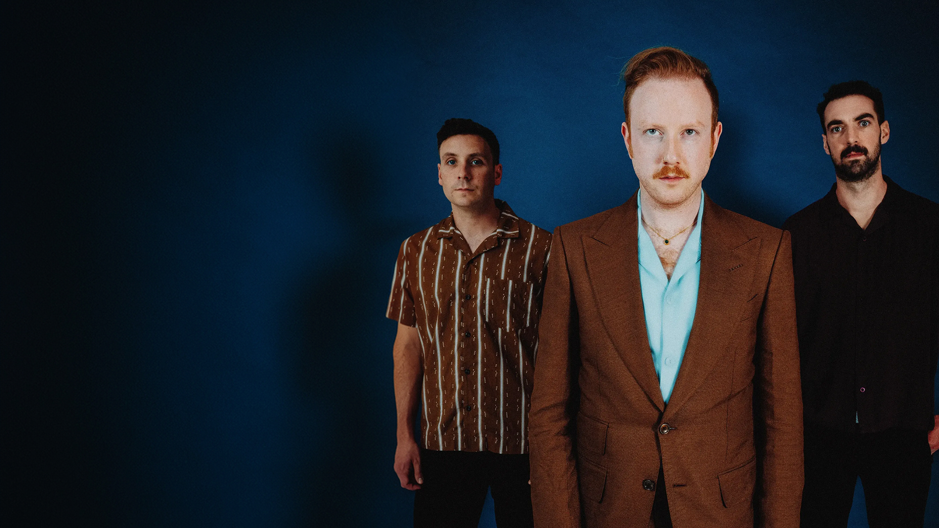 Two Door Cinema Club band members in suits, standing side by side, posing for the camera.