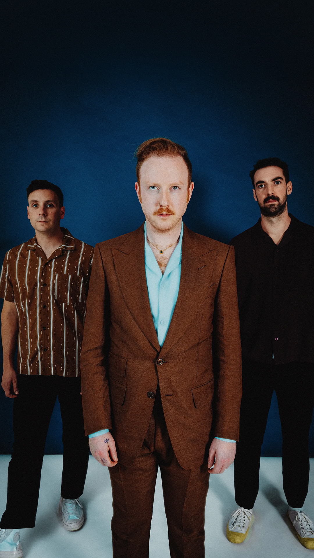 Two Door Cinema Club band members in suits, standing side by side, posing for the camera.